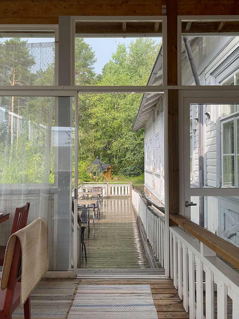 An open glass door and windows leading onto a wooden patio.