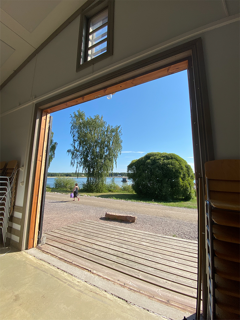 A wide door opening showing trees and water.